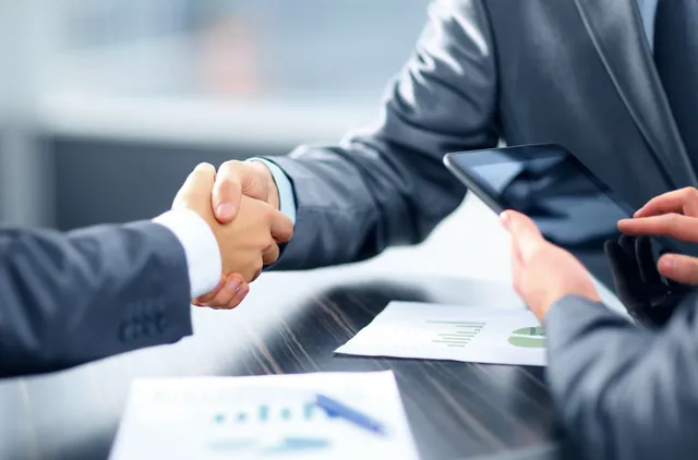 Aperto de mão entre duas pessoas numa reunião de negócios