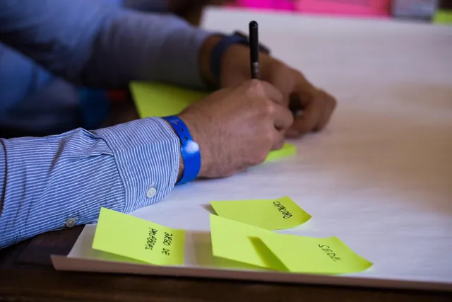 Mão a escrever em notas autocolantes para organizar tarefas